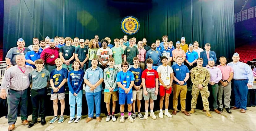 Group of dozens men and boys smiling standing on stage at Miami University