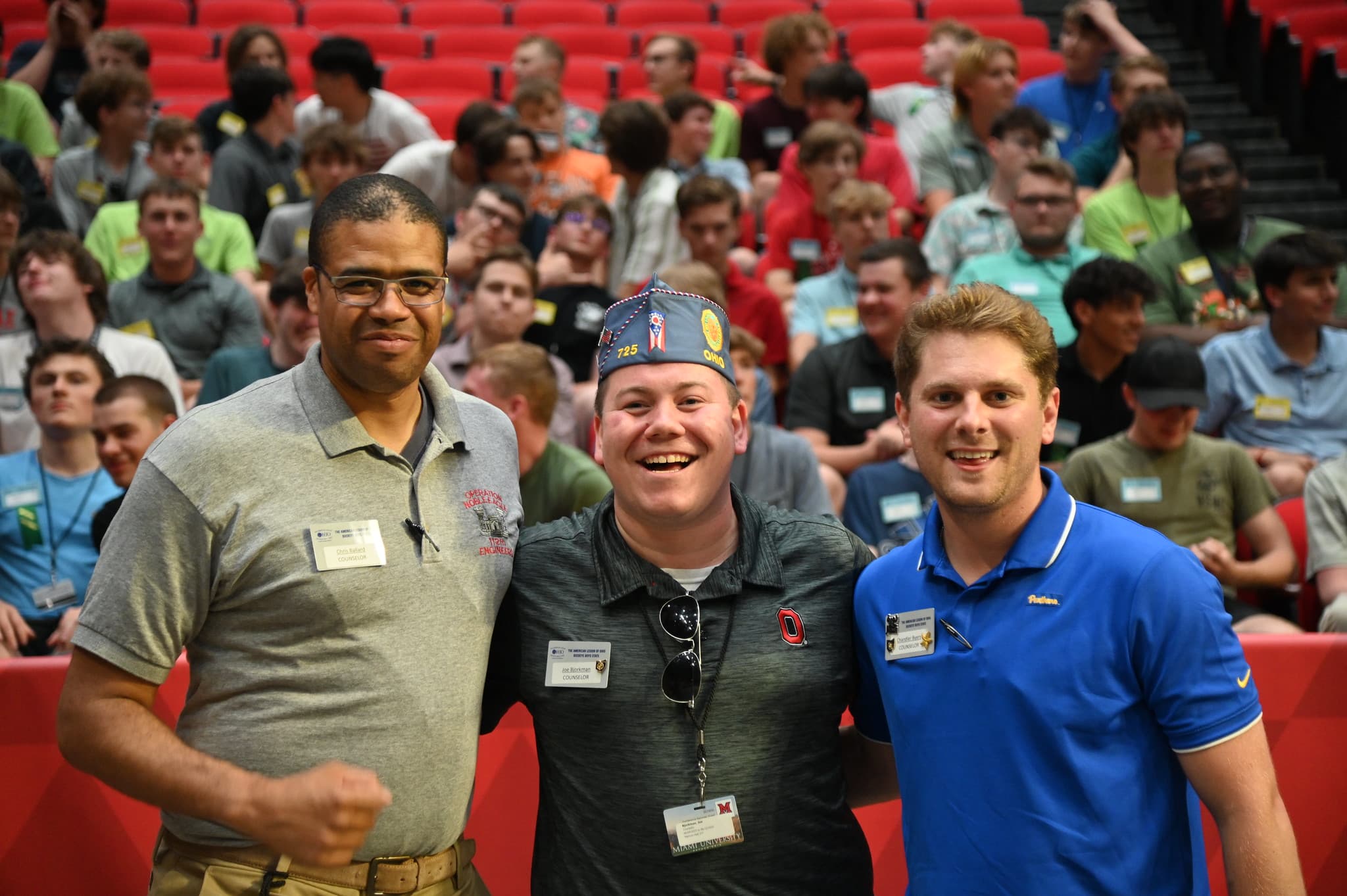 Group of three men smiling at an evening assembly
